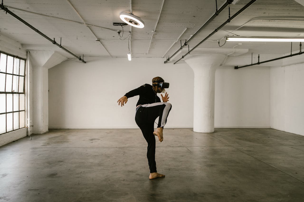 A man engaged in a virtual reality kickboxing session in an empty industrial loft space, wearing VR goggles.
