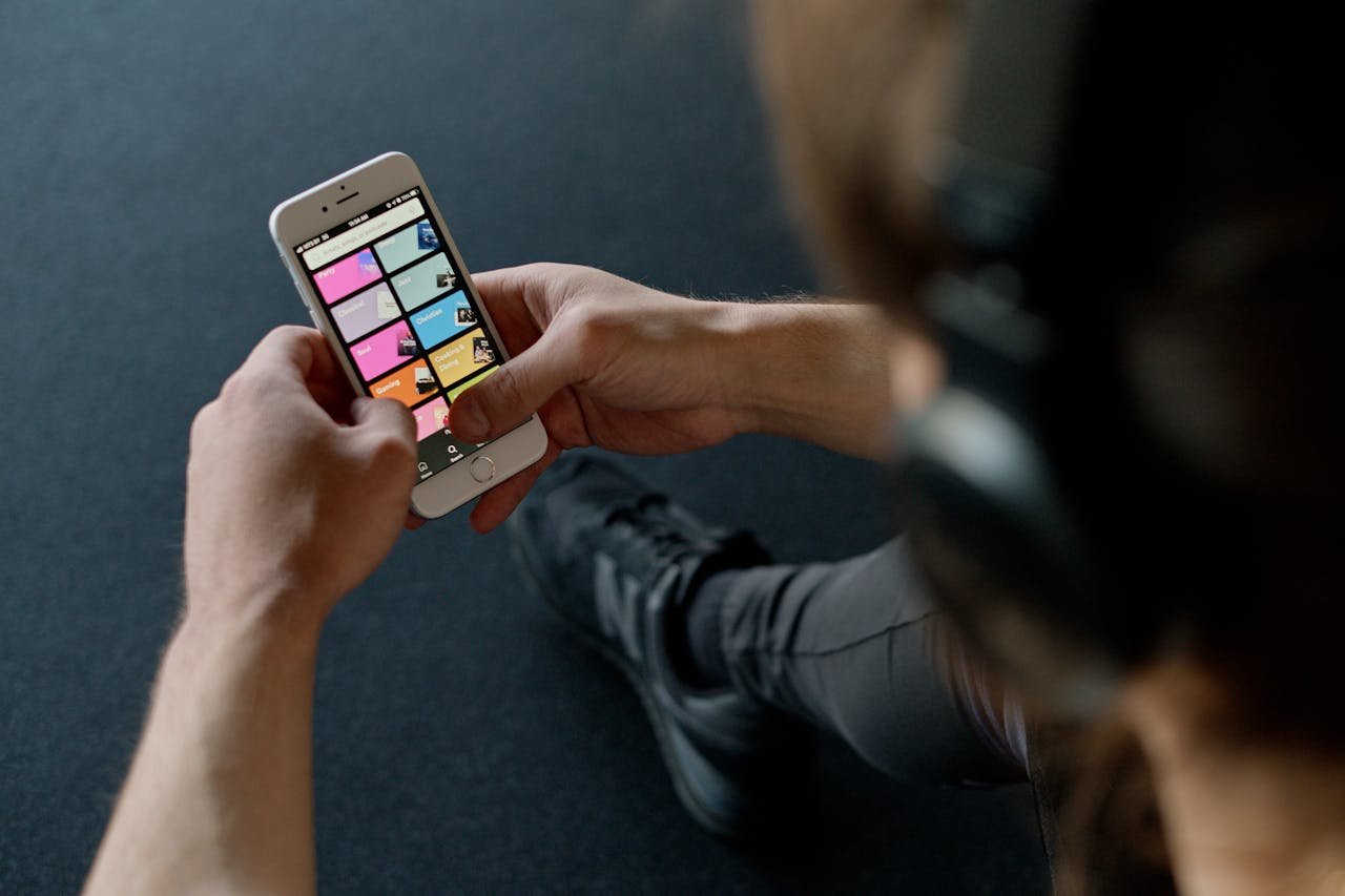 Close-up of a person listening to music on a smartphone while at the gym, focusing on a streaming playlist app.